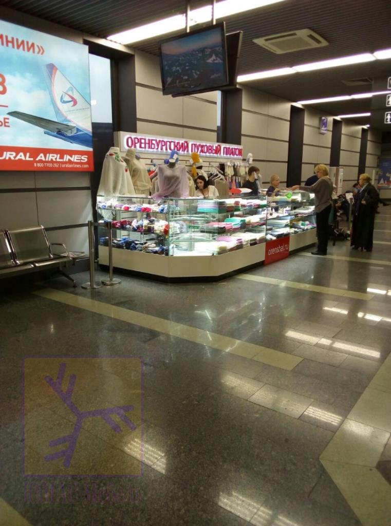Торговый остров с остеклёнными секциями и подсветкой основания расположен в проходе торгового центра — Торговый остров Оренбургский платок